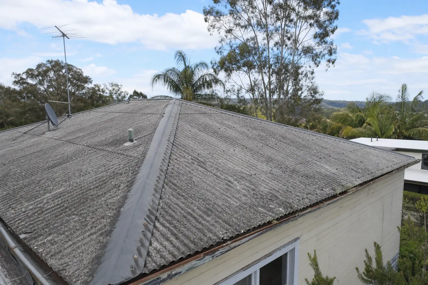 Old grey corrugated asbestos cement roof on a weathered single-storey Central Coast home