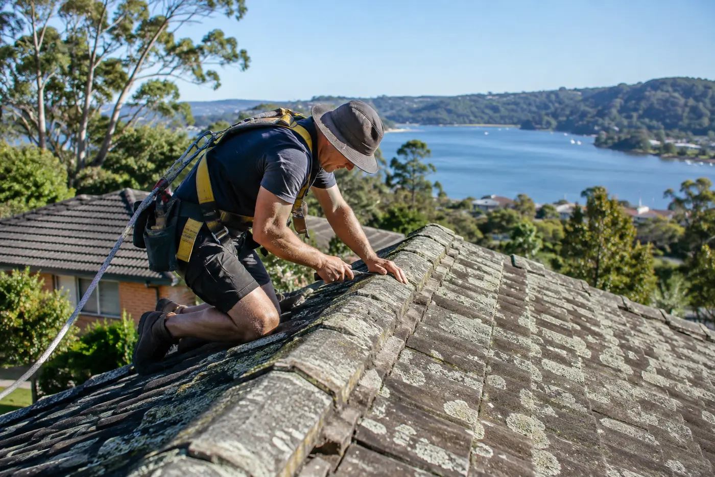 Roofer walking the weathered concrete tile roof of an older Central Coast home during a pre-purchase inspection