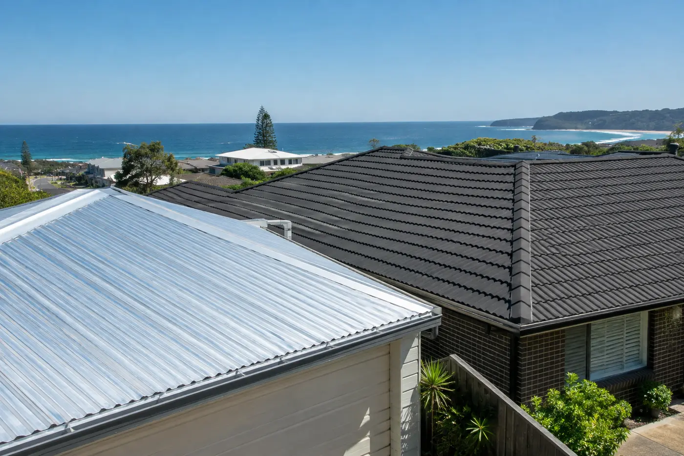 A silver Zincalume garage roof next to a charcoal Colorbond house roof in a coastal Central Coast street