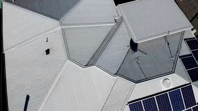 Aerial view of a Kincumber metal roof with Windspray and darker sections, and solar panels