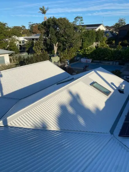 Light coloured metal re-roof with a skylight, looking out over neighbouring homes