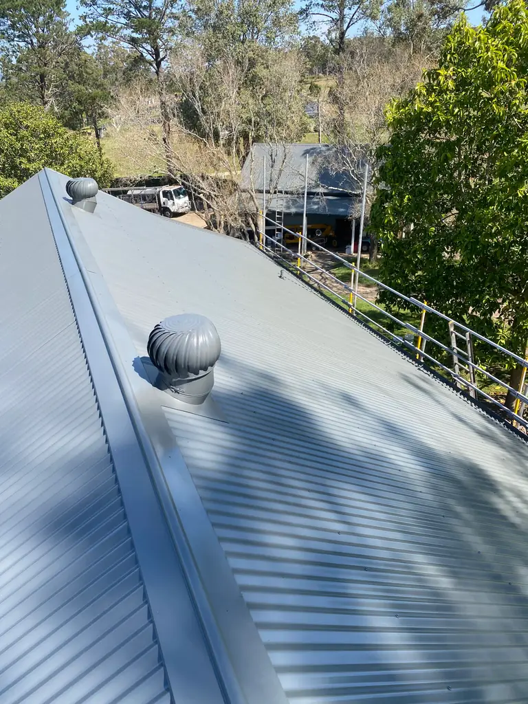 Metal roof on a Somersby acreage home finished in an even blue grey, whirlybird and ridge capping in place